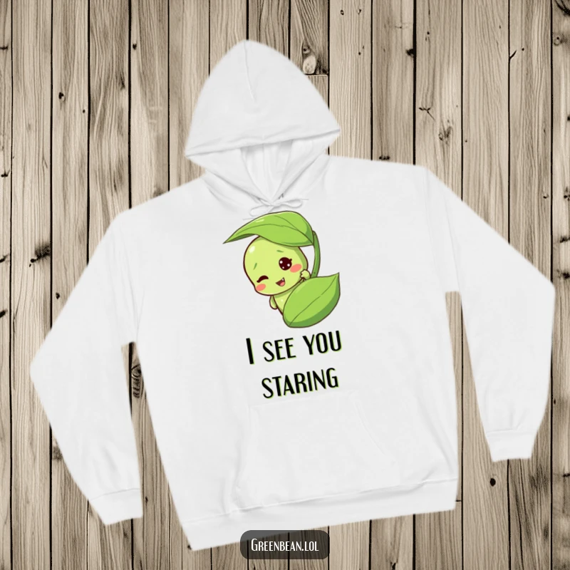 Funny green bean hoodie with a mischievous character peeking from behind a leaf. Cozy and humorous apparel.